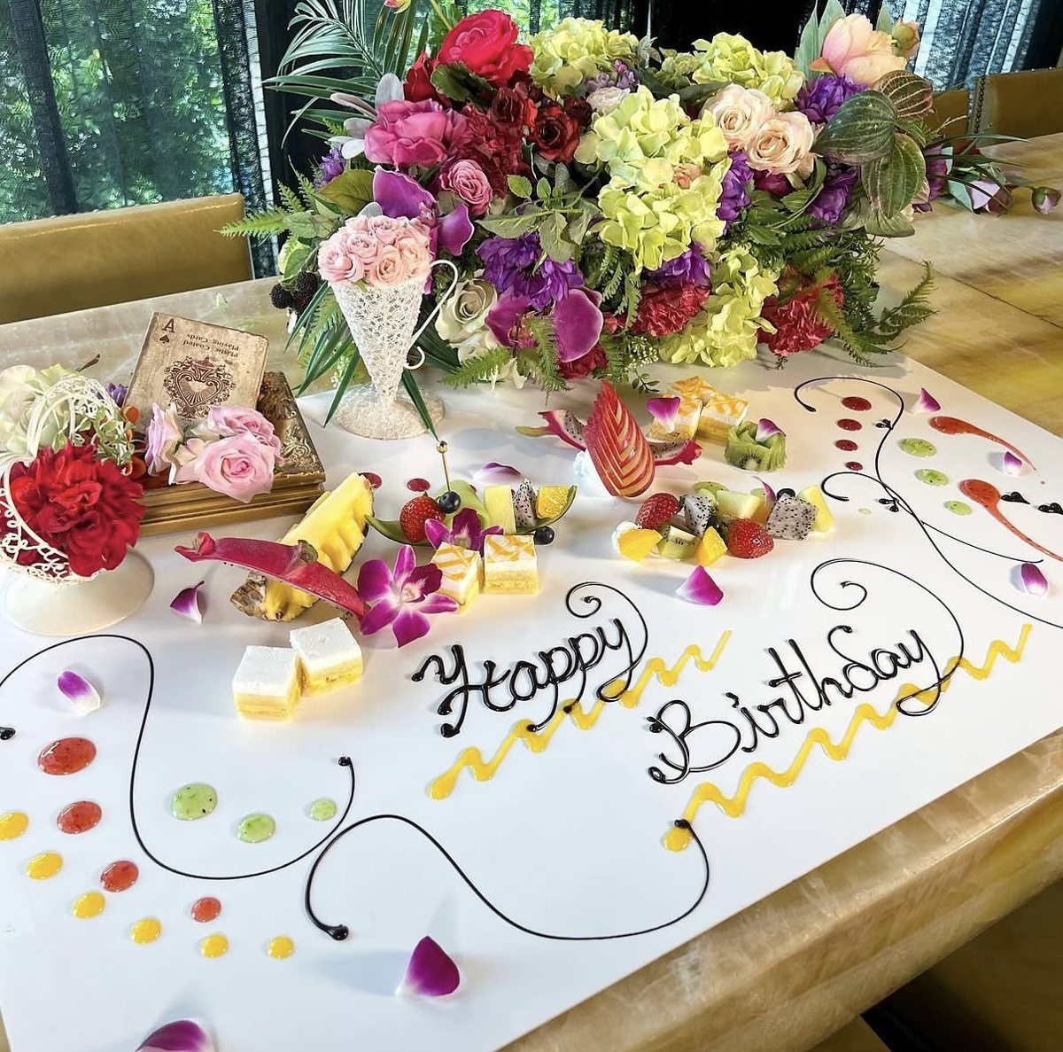 大理石のテーブルいっぱいに描いたHappy Birthdayのテーブルアート。花とフルーツ、ケーキ